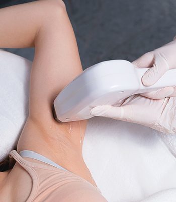 A photo of a young woman at salon having a laser hair removal procedure on armpits .